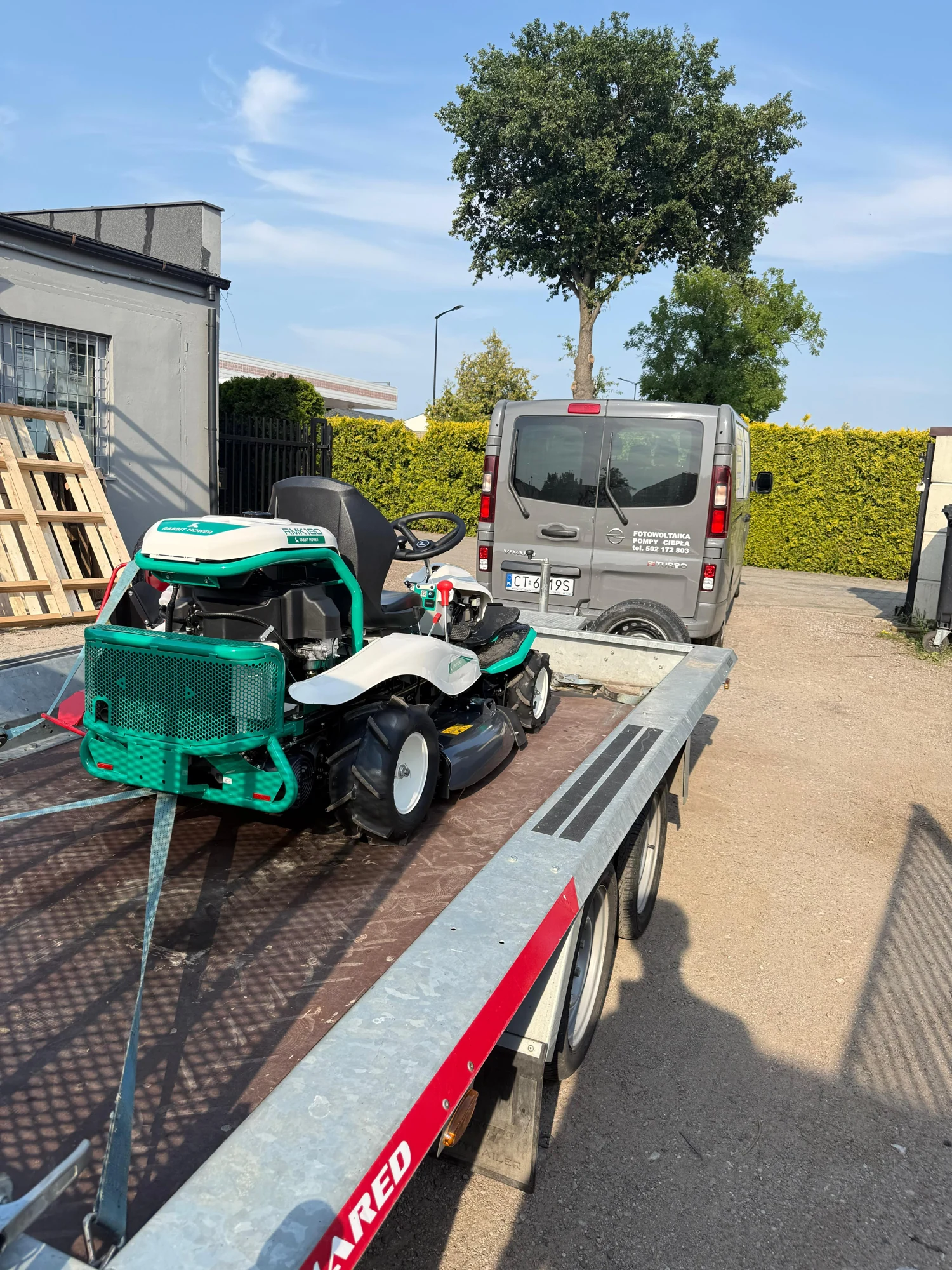 Własna kosiarka Orec CK Energia na przyczepie transportowej przy firmowym samochodzie